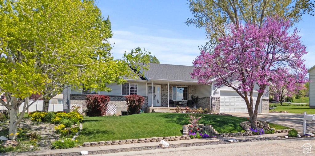 View of front of home with brick siding, an attached garage, a front yard, concrete driveway, and roof with shingles