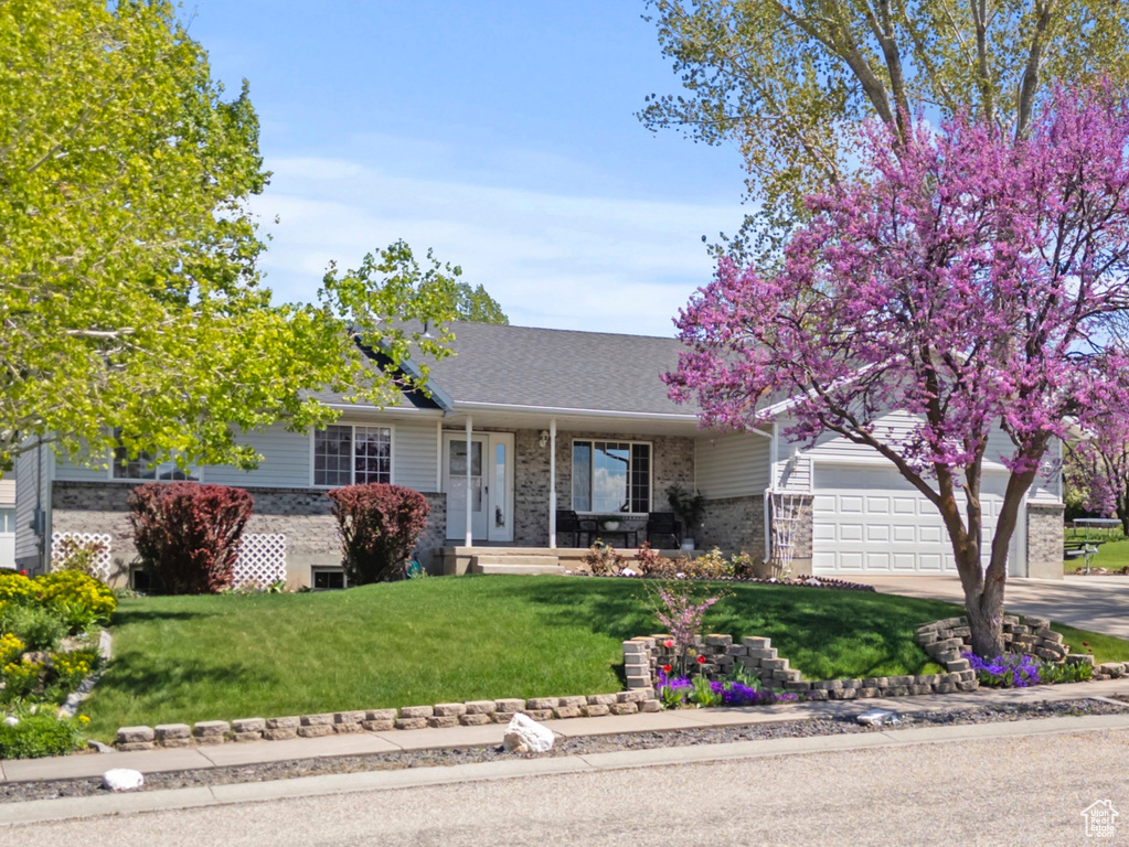 View of front of property featuring brick siding, covered porch, a front yard, concrete driveway, and roof with shingles