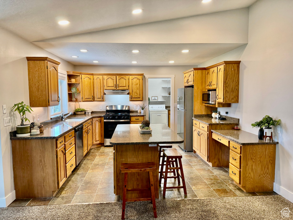Kitchen with stainless steel appliances, washer / clothes dryer, under cabinet range hood, a kitchen island, and recessed lighting