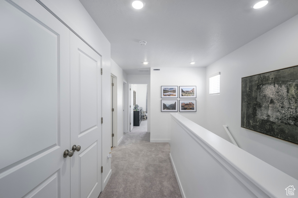Hall with light colored carpet, an upstairs landing, baseboards, and recessed lighting