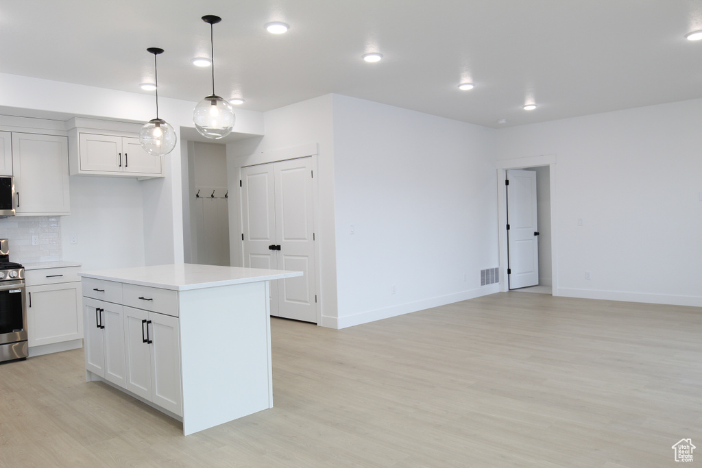 Kitchen with light countertops, visible vents, tasteful backsplash, light wood-style floors, and electric range