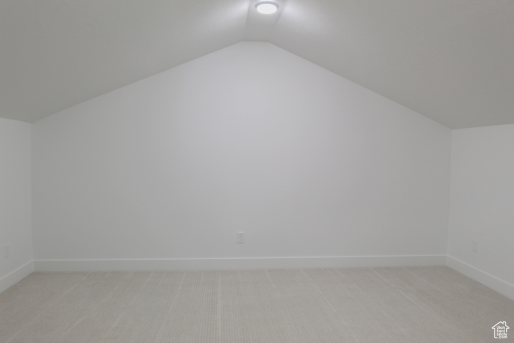 Bonus room featuring light carpet, baseboards, and vaulted ceiling