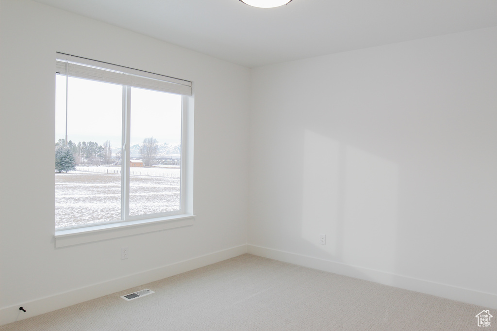 Carpeted spare room featuring baseboards and visible vents