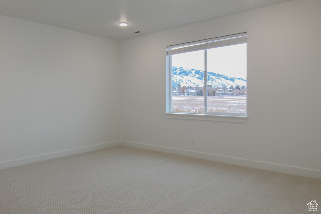 Spare room featuring light carpet and baseboards