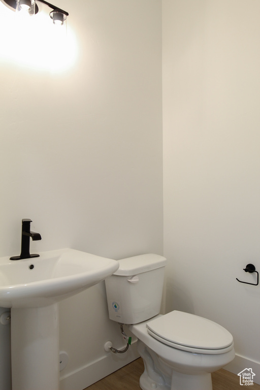Bathroom with baseboards, wood finished floors, toilet, and a sink