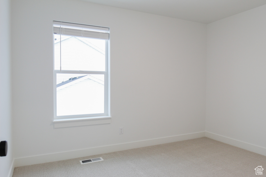 Unfurnished room featuring light carpet, baseboards, visible vents, and plenty of natural light