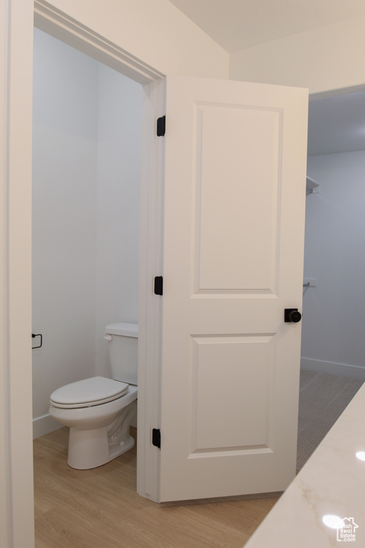 Bathroom featuring baseboards, wood finished floors, and toilet