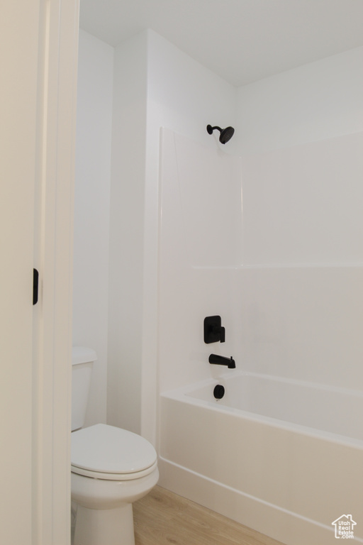Full bath featuring toilet, shower / bathing tub combination, and wood finished floors