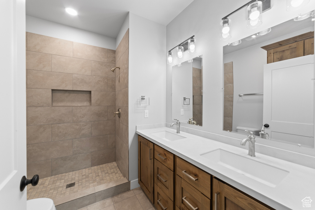 Full bath featuring a tile shower, a sink, toilet, and tile patterned floors