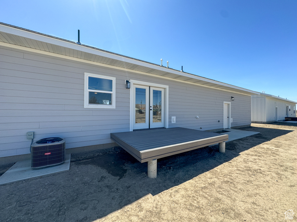 Rear view of house featuring a deck, french doors, and central AC