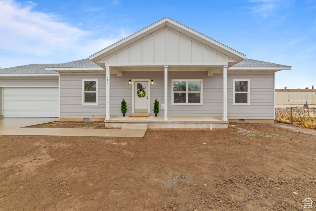 View of front of property featuring covered porch, concrete driveway, crawl space, and a garage