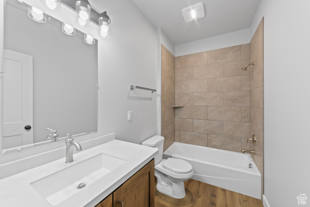 Full bath featuring toilet, vanity, washtub / shower combination, and wood finished floors
