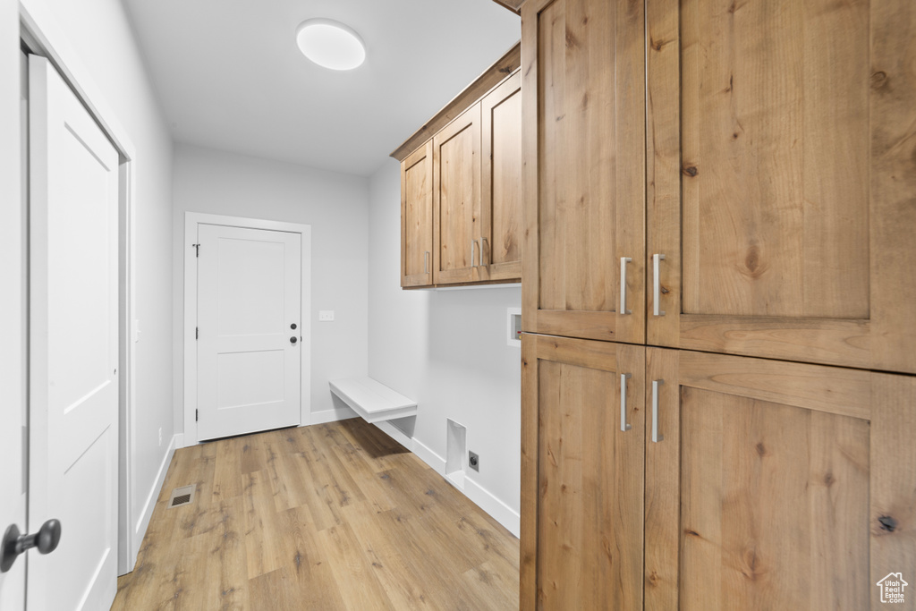 Interior space with hookup for an electric dryer, light wood-style floors, visible vents, cabinet space, and washer hookup
