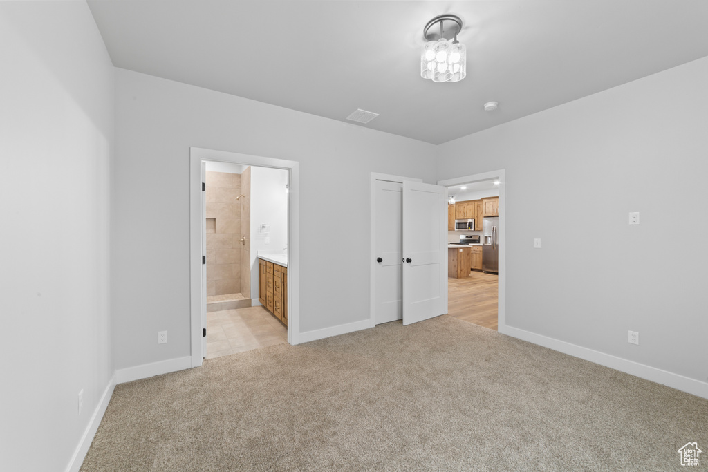 Unfurnished bedroom featuring stainless steel fridge with ice dispenser, baseboards, light colored carpet, and visible vents