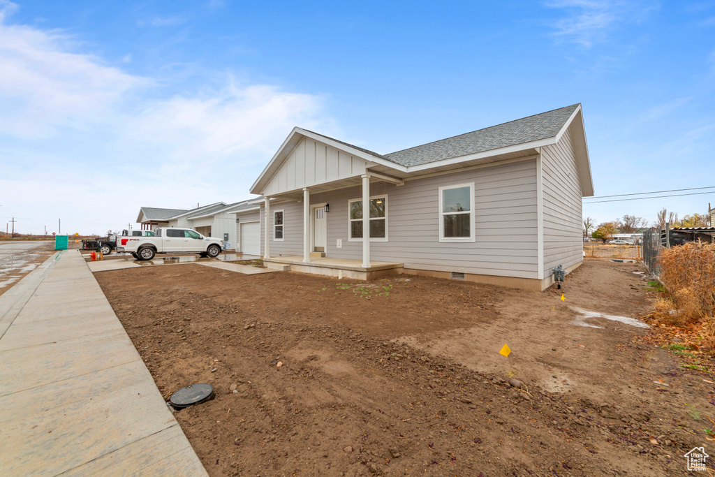 View of front facade featuring roof with shingles, an attached garage, board and batten siding, crawl space, and a porch