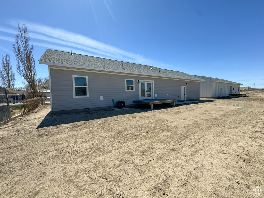 Rear view of property featuring french doors, a shingled roof, and cooling unit