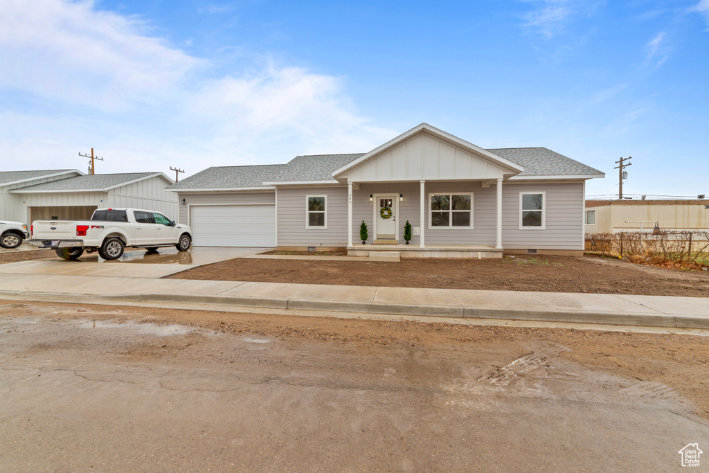 View of front of house with concrete driveway, board and batten siding, crawl space, a garage, and a shingled roof