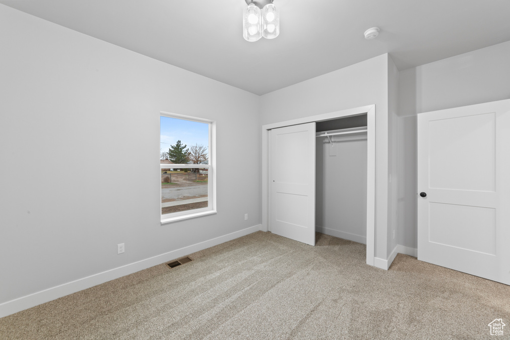Unfurnished bedroom with baseboards, carpet flooring, visible vents, and a closet