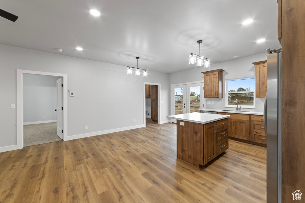 Kitchen with light countertops, a sink, a center island, and wood finished floors