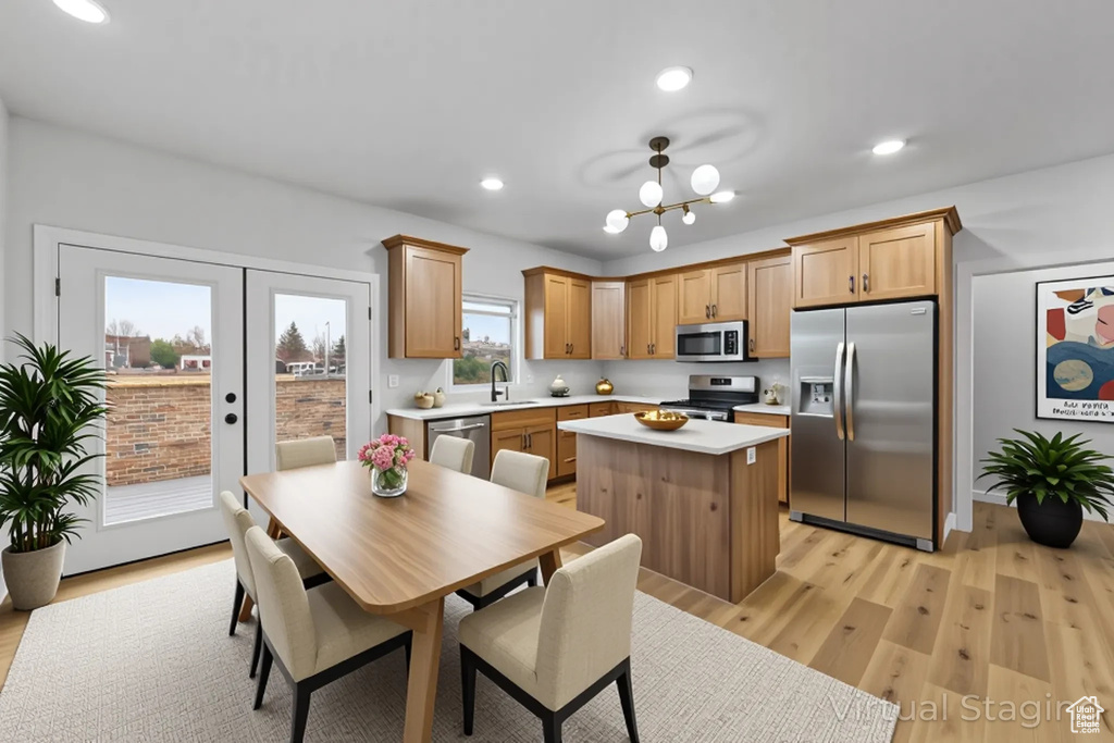 Kitchen featuring light wood-type flooring, light countertops, a kitchen island, appliances with stainless steel finishes, and a sink