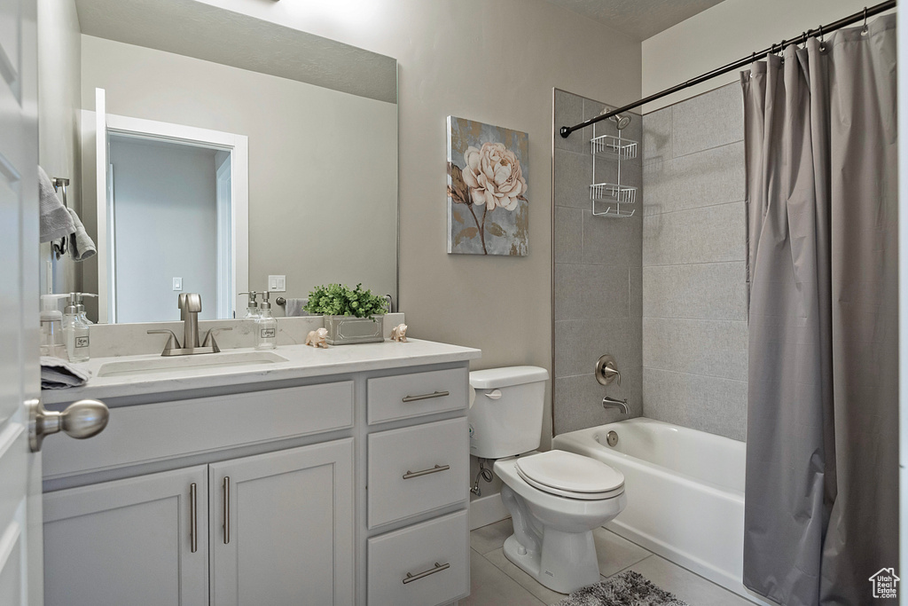 Bathroom with shower / bath combination with curtain, tile patterned floors, toilet, and vanity