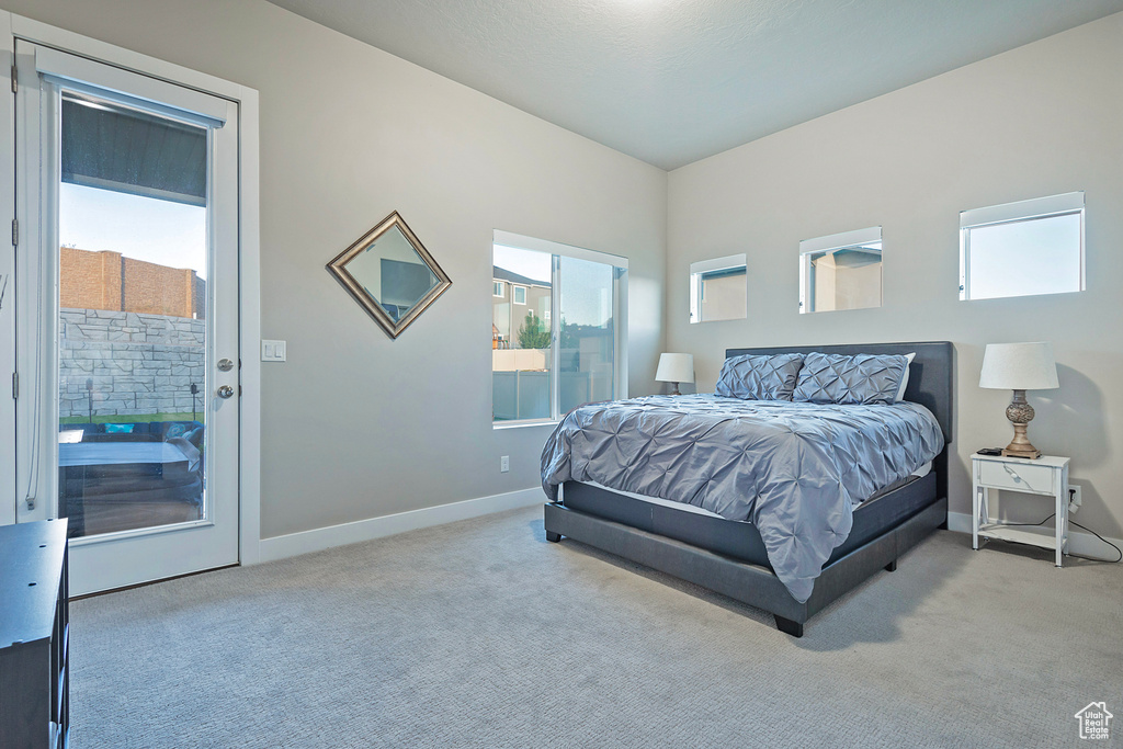 Carpeted bedroom with baseboards and access to exterior