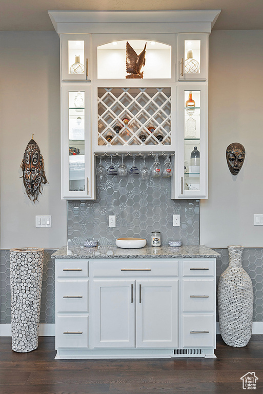 Bar with dark wood-style flooring, indoor wet bar, and tasteful backsplash