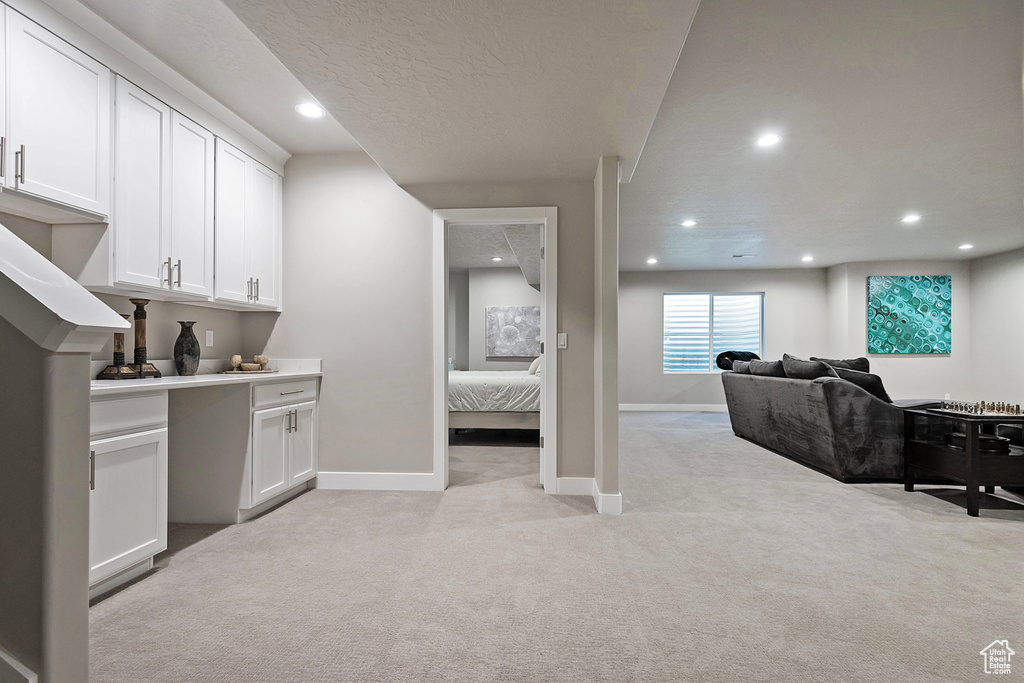 Interior space with light carpet, a textured ceiling, baseboards, and recessed lighting