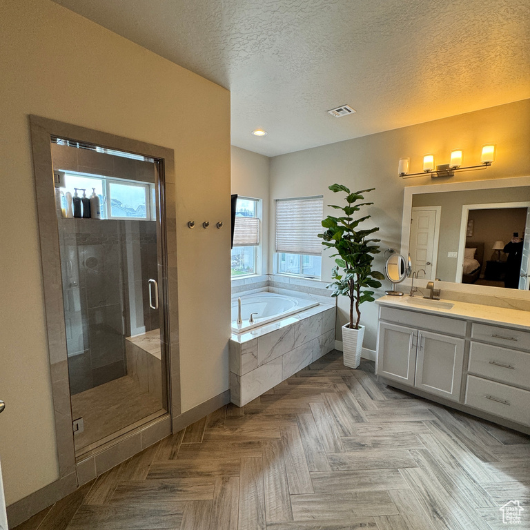 Bathroom featuring vanity, a textured ceiling, a stall shower, a garden tub, and visible vents