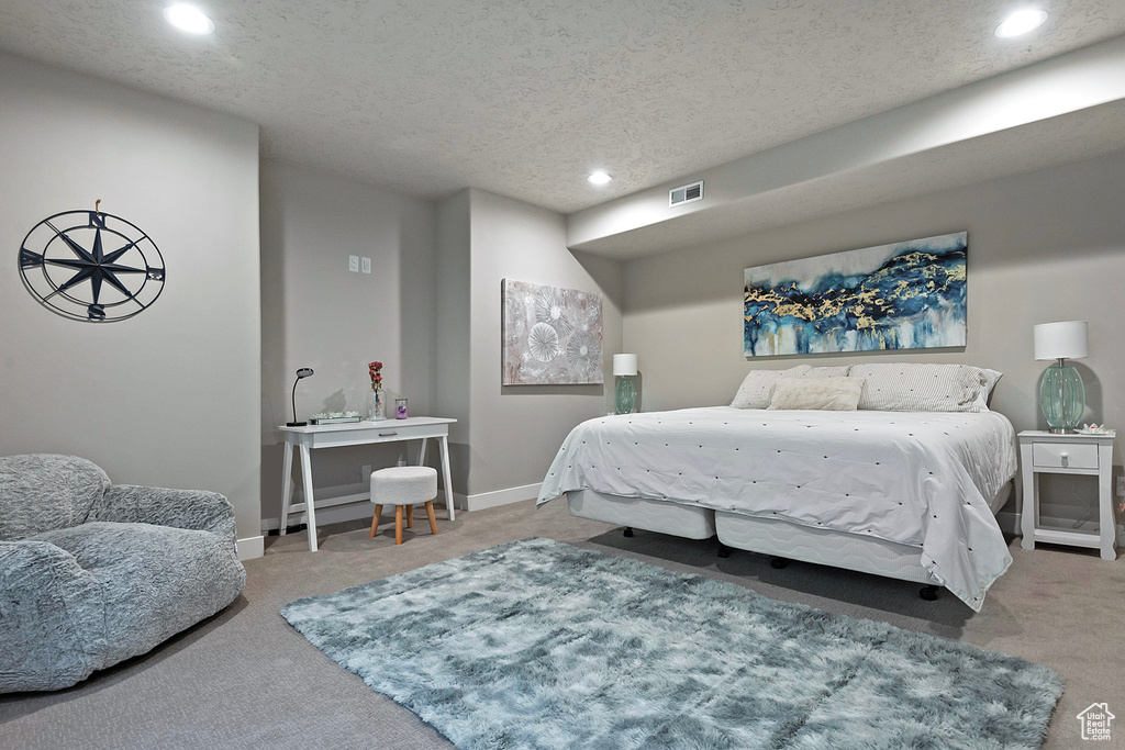 Bedroom with baseboards, visible vents, carpet, and a textured ceiling