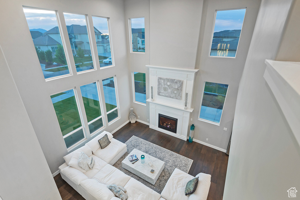 Living room with baseboards, a warm lit fireplace, and wood finished floors