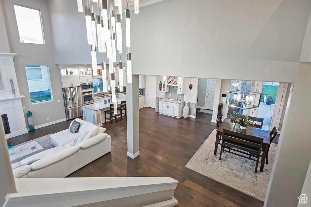 Living room featuring baseboards, a towering ceiling, dark wood-type flooring, and an inviting chandelier