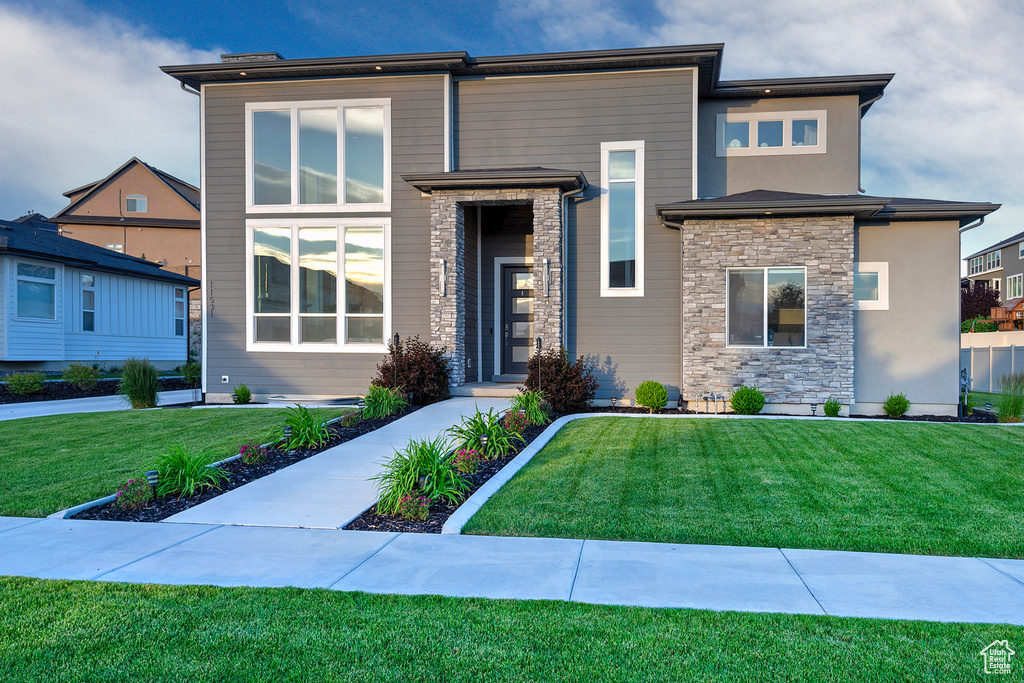 View of front of house with stone siding and a front lawn