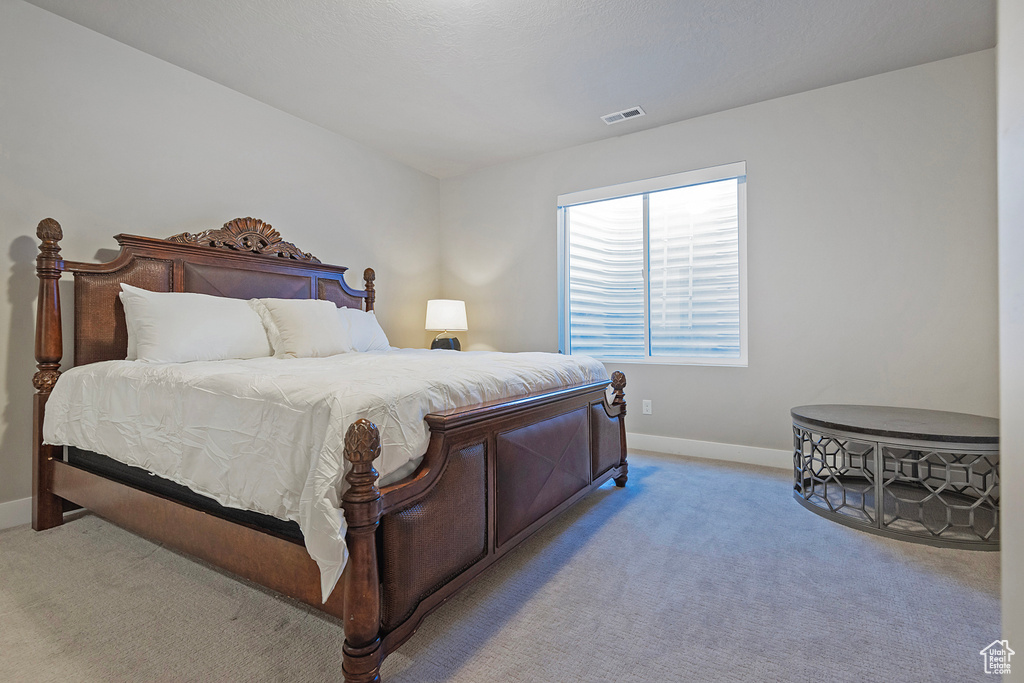 Carpeted bedroom with baseboards and visible vents