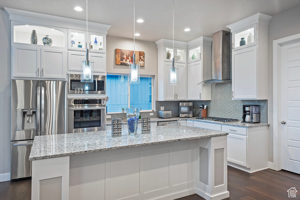Kitchen featuring white cabinets, wall chimney range hood, and appliances with stainless steel finishes