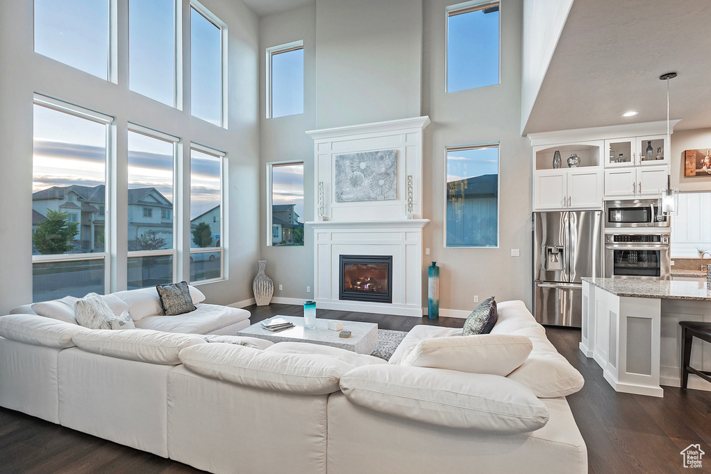 Living room featuring baseboards, dark wood-style flooring, a glass covered fireplace, and recessed lighting
