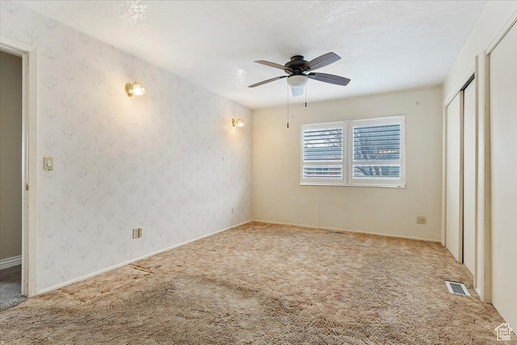 Unfurnished bedroom featuring baseboards, visible vents, wallpapered walls, and carpet floors