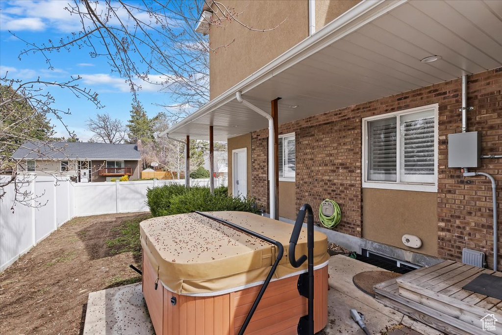 View of patio with fence and a hot tub