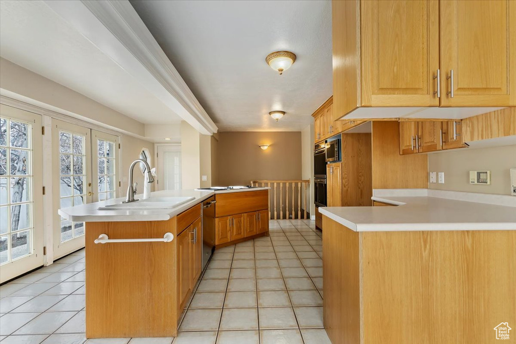 Kitchen featuring light countertops, stainless steel dishwasher, a sink, light tile patterned flooring, and a peninsula