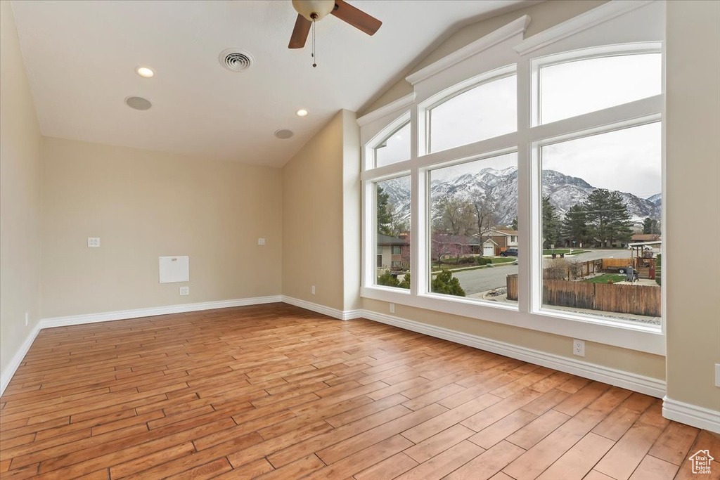 Unfurnished room with lofted ceiling, a mountain view, light wood finished floors, ceiling fan, and visible vents