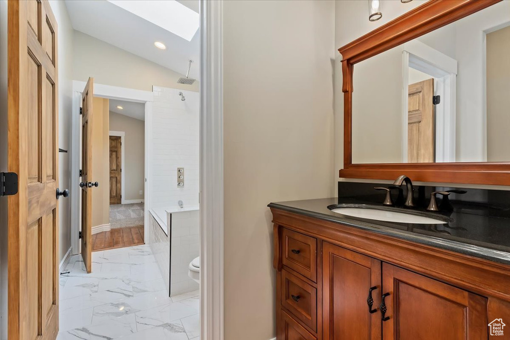 Bathroom featuring vanity, toilet, marble finish floor, a skylight, and  shower combination