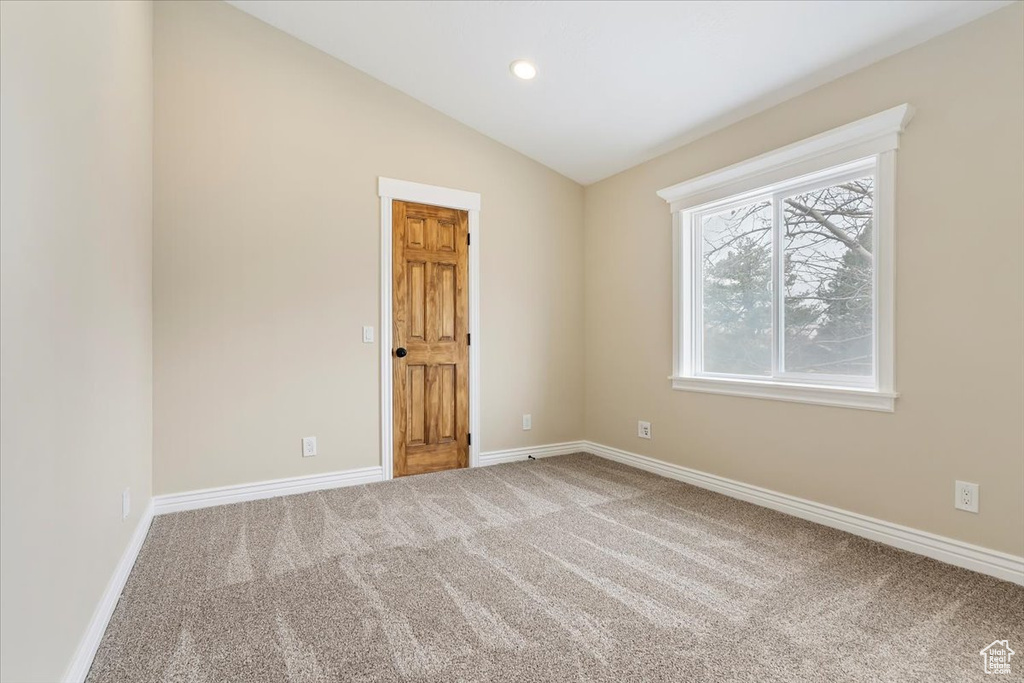 Carpeted empty room featuring baseboards, lofted ceiling, and recessed lighting