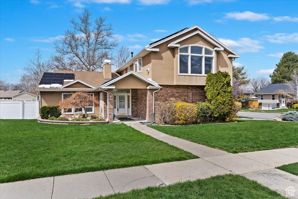View of front of property featuring a front yard, stucco siding, fence, and a chimney