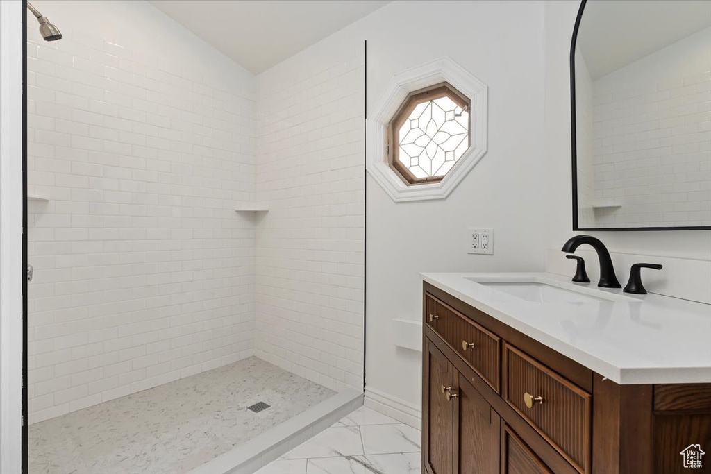 Full bathroom with marble finish floor, a stall shower, and vanity