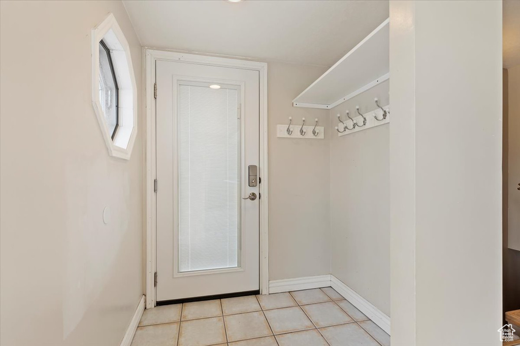 Doorway featuring light tile patterned floors and baseboards