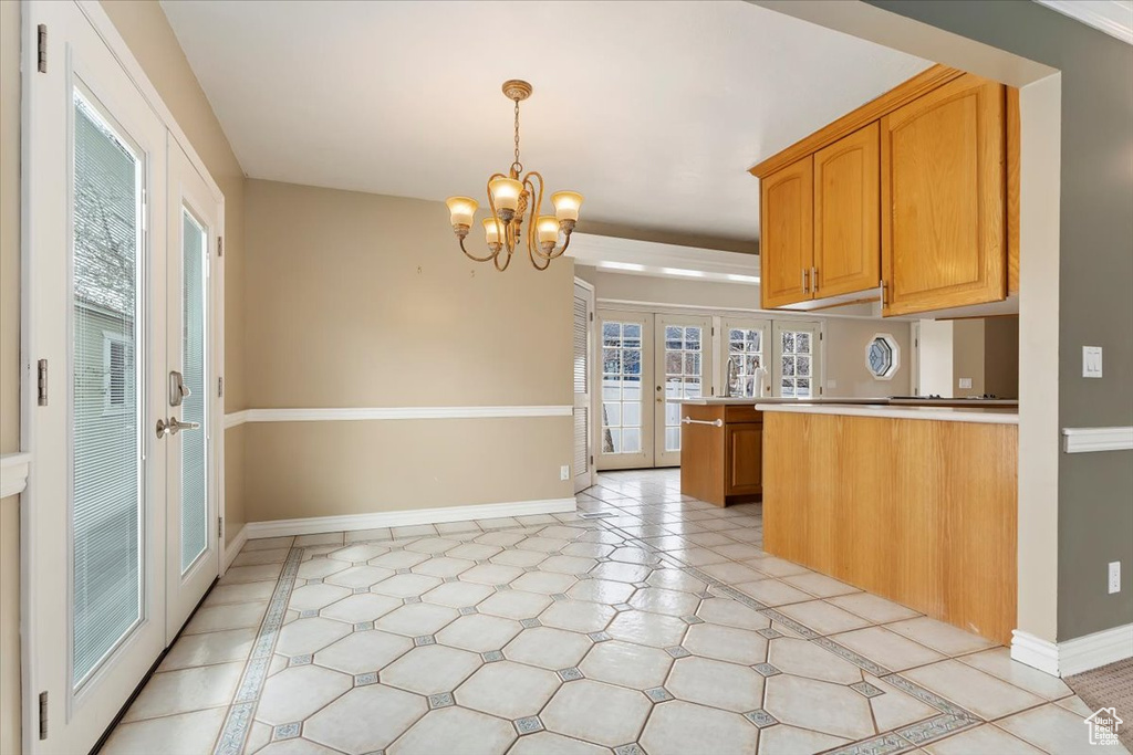 Kitchen with a notable chandelier, light countertops, french doors, hanging light fixtures, and baseboards