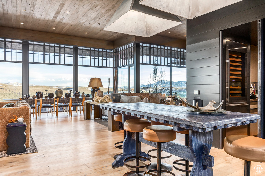 Bar area with hardwood / wood-style floors, a mountain view, wood ceiling, a wall of windows, and a high ceiling
