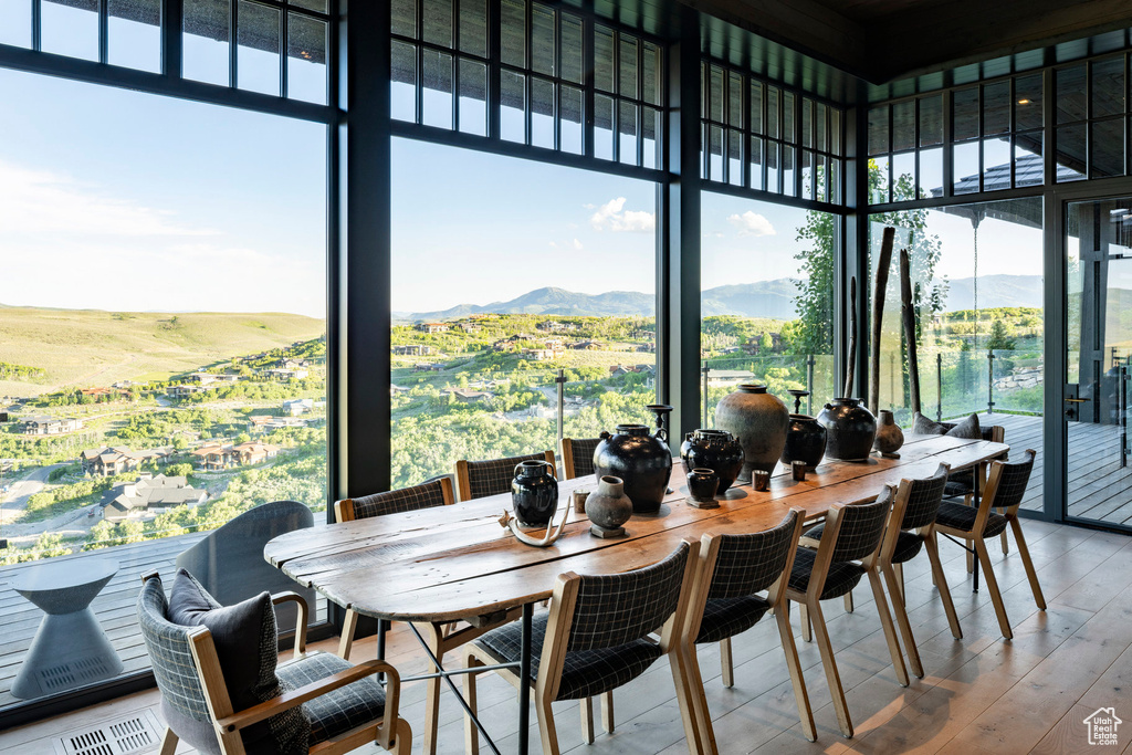 Dining room featuring healthy amount of natural light, a wall of windows, wood finished floors, a high ceiling, and a mountain view