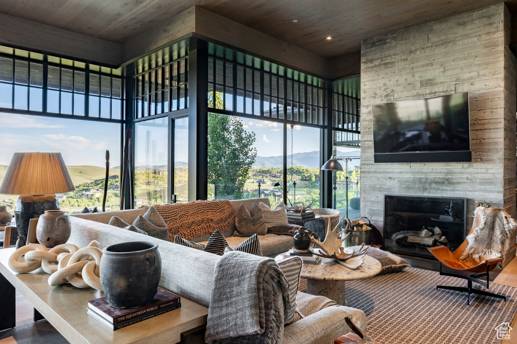 Living room with a towering ceiling, wood ceiling, plenty of natural light, a fireplace, and wood finished floors