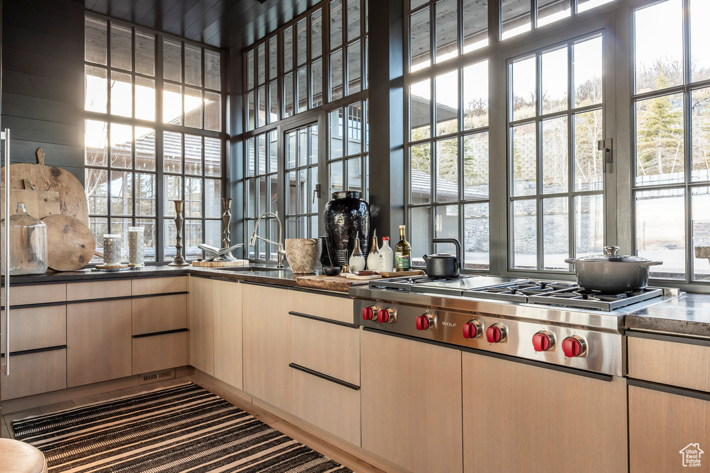 Kitchen featuring stainless steel gas cooktop, carpet, light brown cabinets, and a high ceiling
